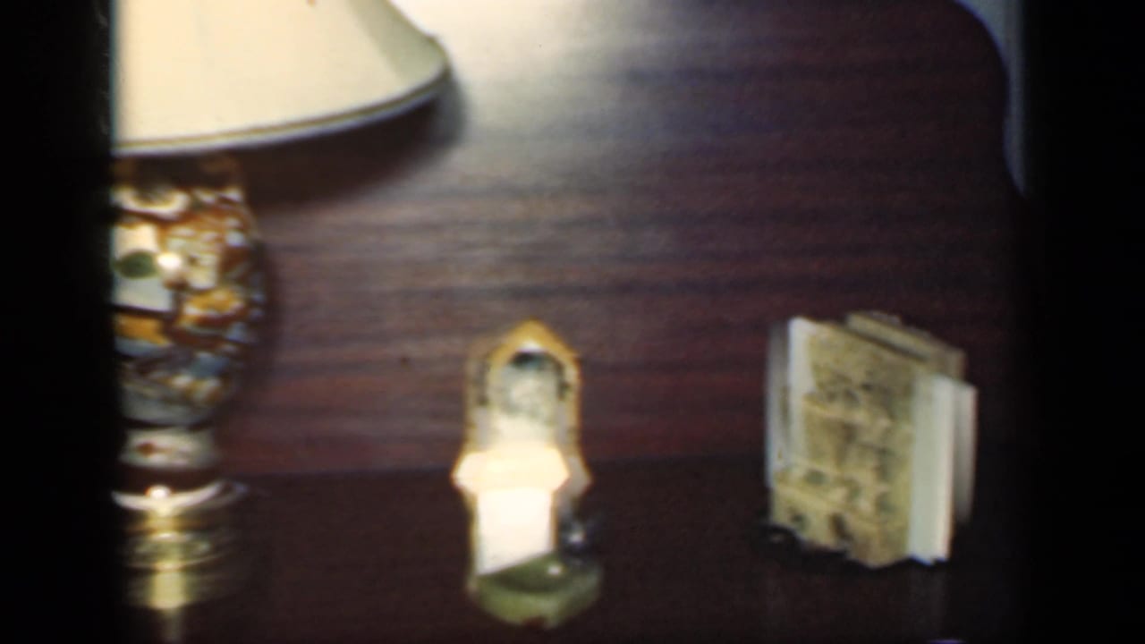 Wooden tabletop with a lamp, small figurines and a small book or framed object.