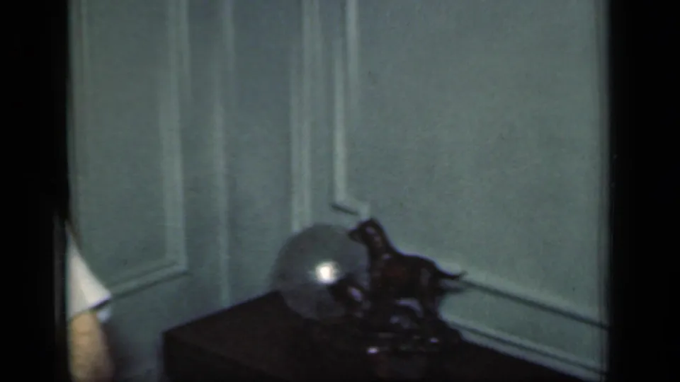 A 1949 New York home interior shows pale wall paneling, a dark table, and a decorative object with a round reflective element.