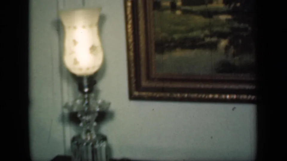 A 1949 New York home interior shows a lit crystal-style lamp near a framed landscape painting on pale paneled walls.