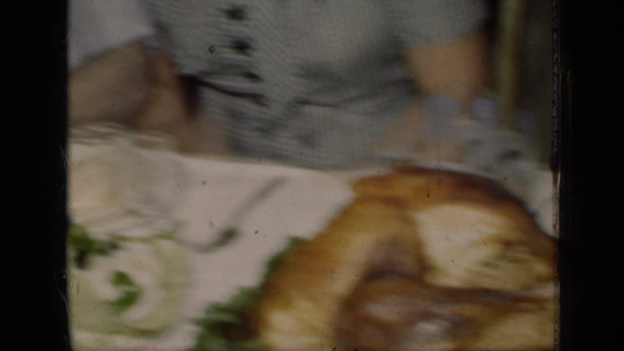 Woman in striped dress serving a roasted turkey at a holiday table.