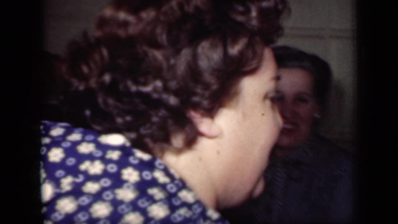1949 New York home-movie frame showing a woman in profile near a dining table, with a partially visible person behind her.