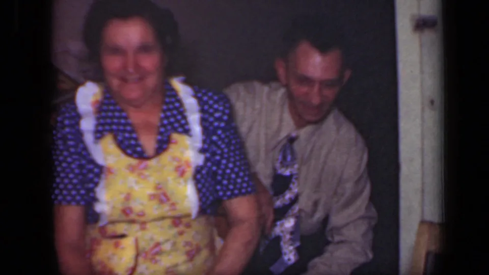In this 1949 New York home interior, the woman smiles toward the camera while the man in a shirt and tie sits slightly behind her.