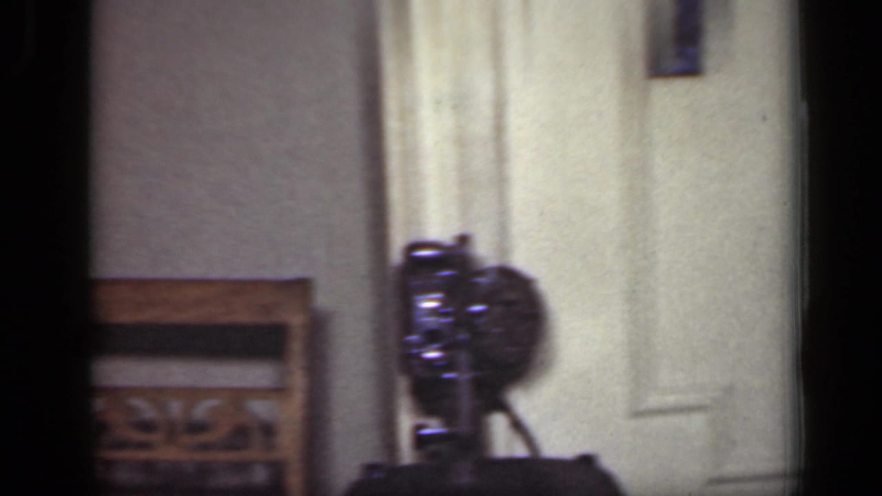 Interior room detail with a closed door and small camera-like object on a table.