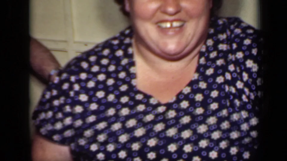 1949 New York frame showing a smiling woman in a blue-and-white floral dress seated in a private interior.