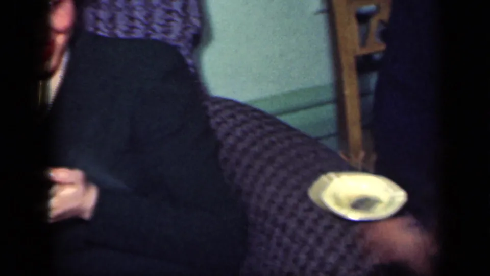 A woman in dark clothing sits on a patterned armchair in a private New York home interior, with a small dish visible nearby.