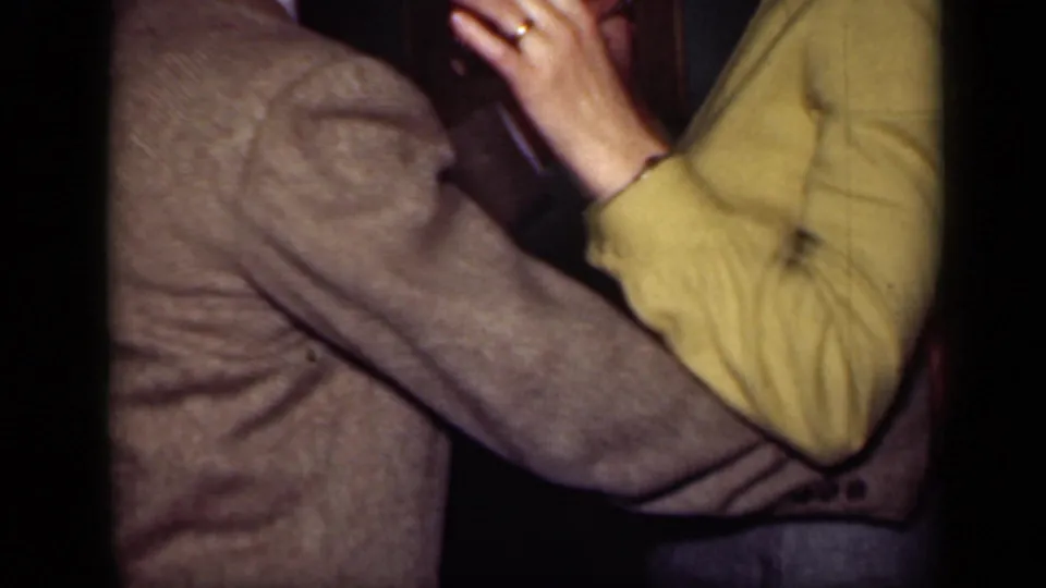 The 1949 home-movie frame shows the couple dancing at close range, with clasped hands and the woman's yellow jacket prominent.