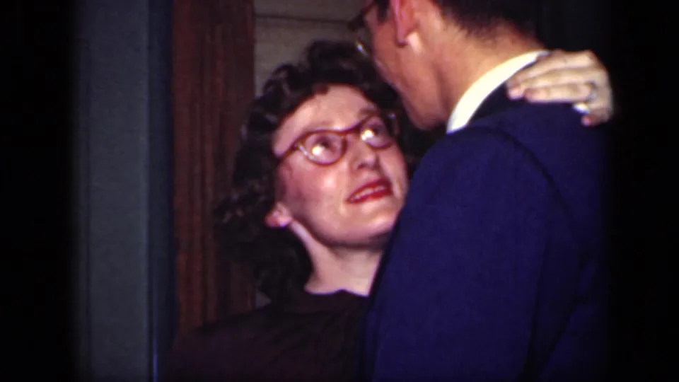 The woman looks up at her partner with one hand on his shoulder as they dance in a dim interior associated with 1949 New York metadata.