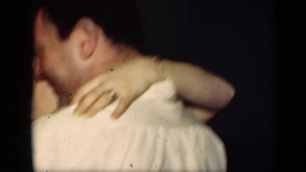 Close view of a couple embracing while dancing in a dim interior.