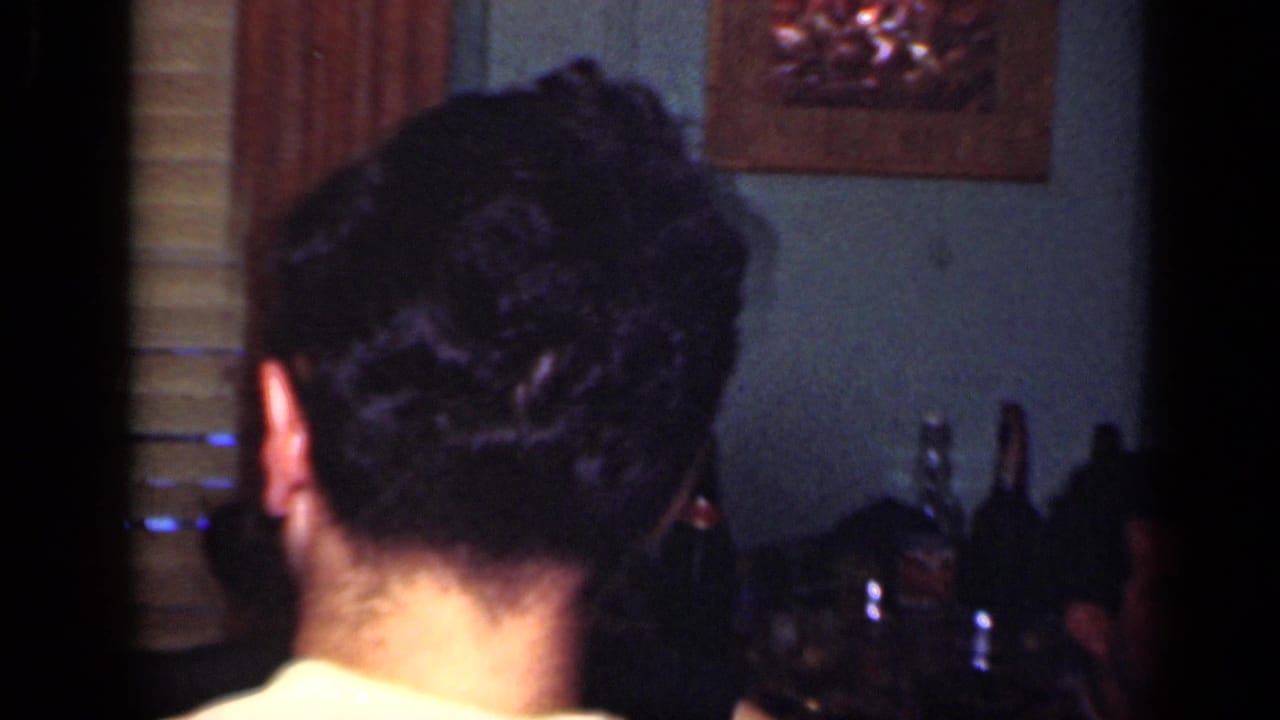 1949 New York indoor party frame with the back of a man's head, bottles along the wall, and framed decor in a dim private room.