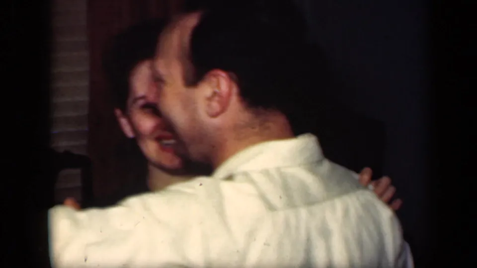 1949 New York home-movie frame showing a smiling woman and a man in a light shirt interacting in a dim private party room.