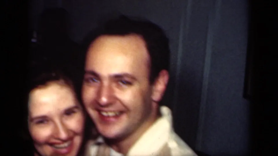 A smiling couple in 1949 New York home-movie footage leans close together in a dim private interior.