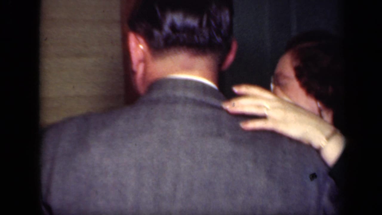 Woman’s hand rests on a suited man’s shoulder while dancing.