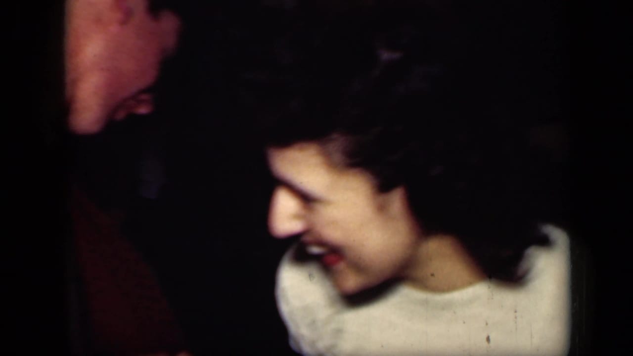 Young woman laughs while facing a man in a dark suit.