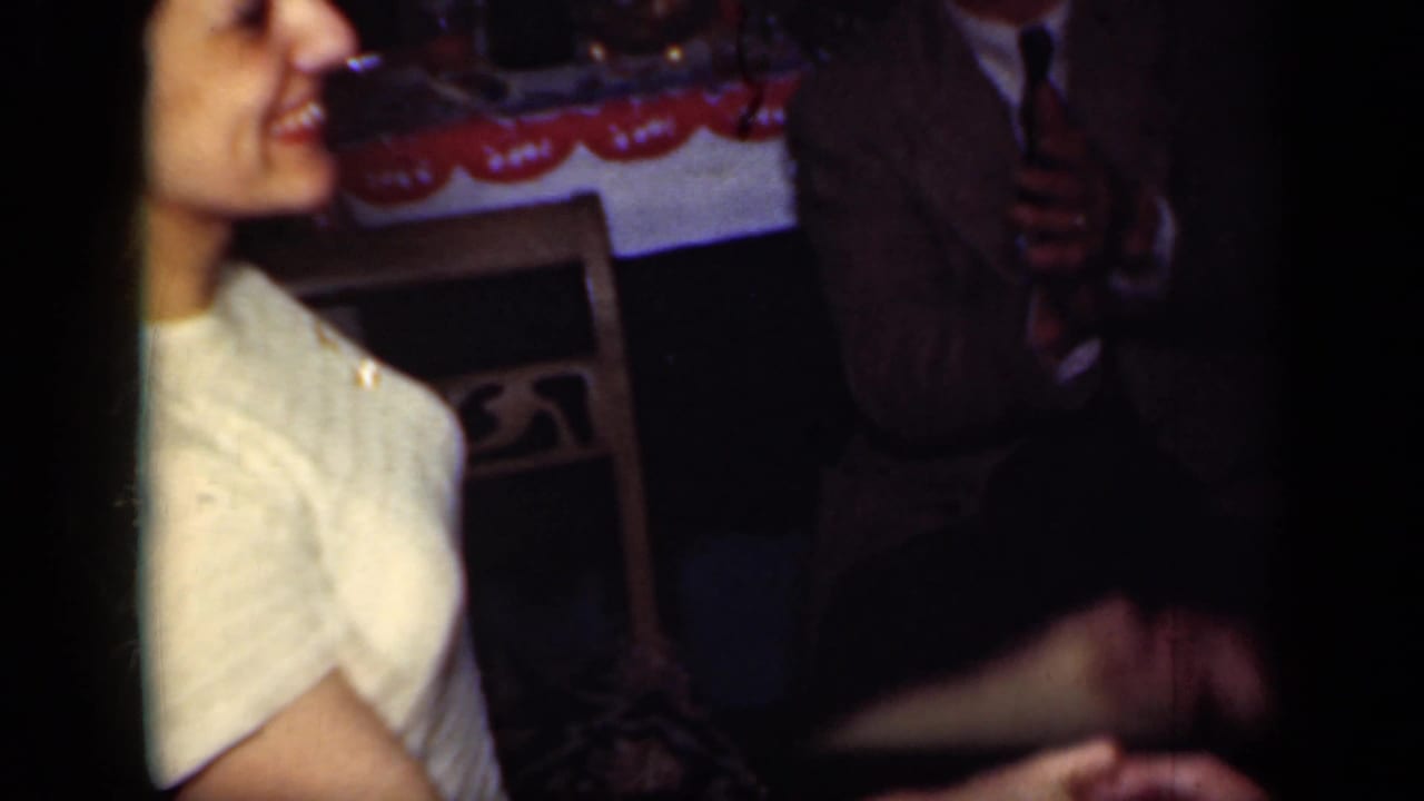 Smiling young female dancer in a light dress near an adult in a suit indoors.