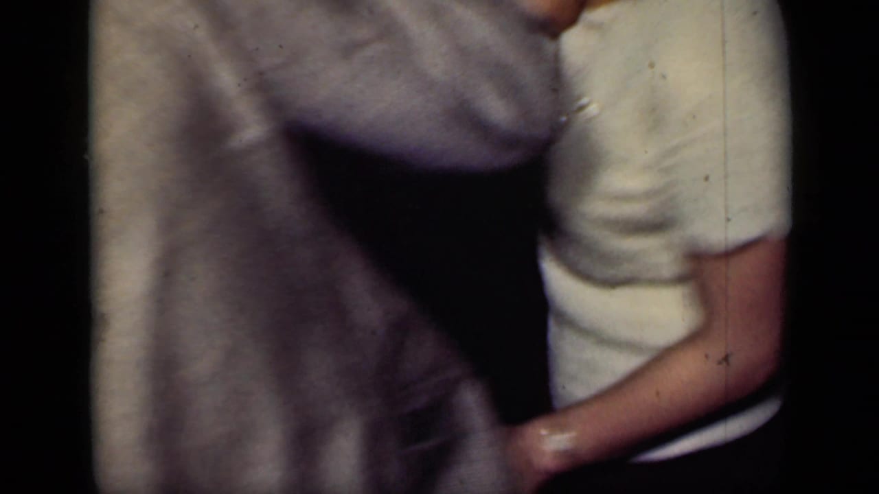 Close view of two dancers clasping hands, with torsos partly cropped.