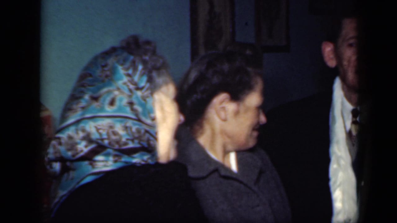 Woman in a blue patterned headscarf faces another woman in a dark coat near a suited man.