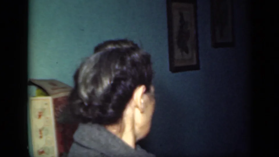 The final 1949 New York 8mm frame shows the back of a woman with dark styled hair inside a private teal-walled room.