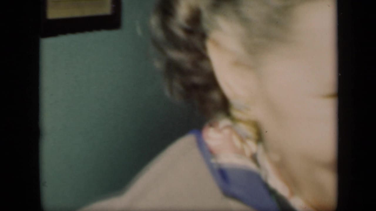 Close, partial view of a braided-haired person near a green interior wall.