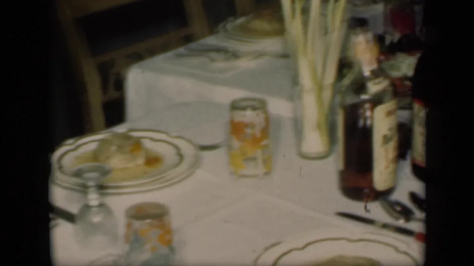 A later table view shows plates, patterned glasses, bottles, silverware, and tall greenery on the white tablecloth inside the private dining room.