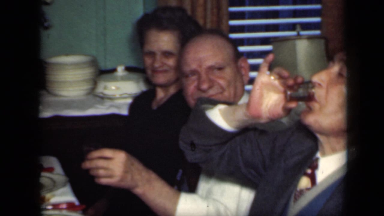Two men and a woman raise or hold drinks during an indoor gathering.