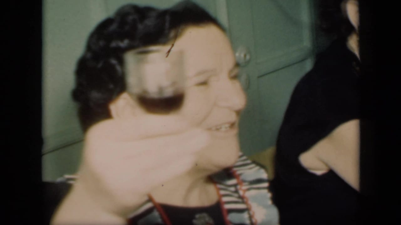 Woman in patterned top holding a glass beside another woman in a dark dress.