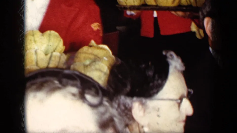 1957 New York banquet footage showing bread trays above the crowd and a man in glasses in a soft, close foreground view.