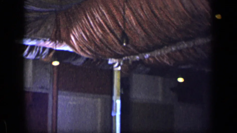 Home-movie frame showing the draped ceiling and dim interior of the New York dinner venue after the people leave view.