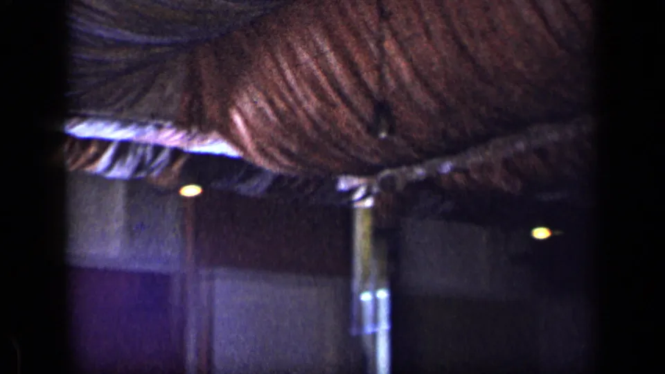 Final 1957 New York home-movie frame focused on draped ceiling fabric and wall panels inside the formal venue.