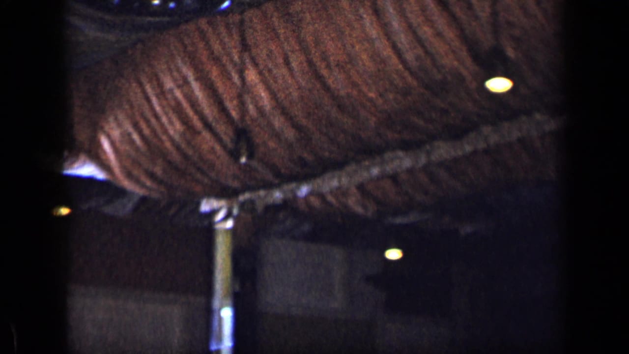 Dim interior ceiling with brown woven material, small lights, and a vertical support pole.