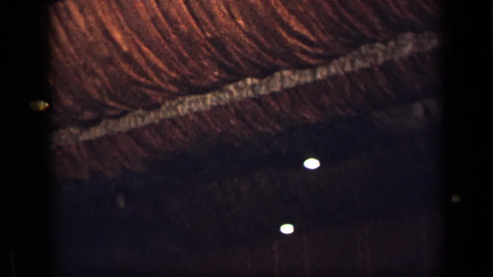 1957 New York 8mm frame with a straw-textured ceiling crossing the upper frame and small lights glowing in the dark interior below.