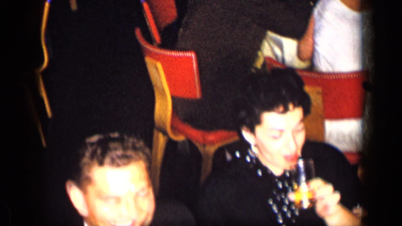 Guests at red chairs, including a woman holding a drink.