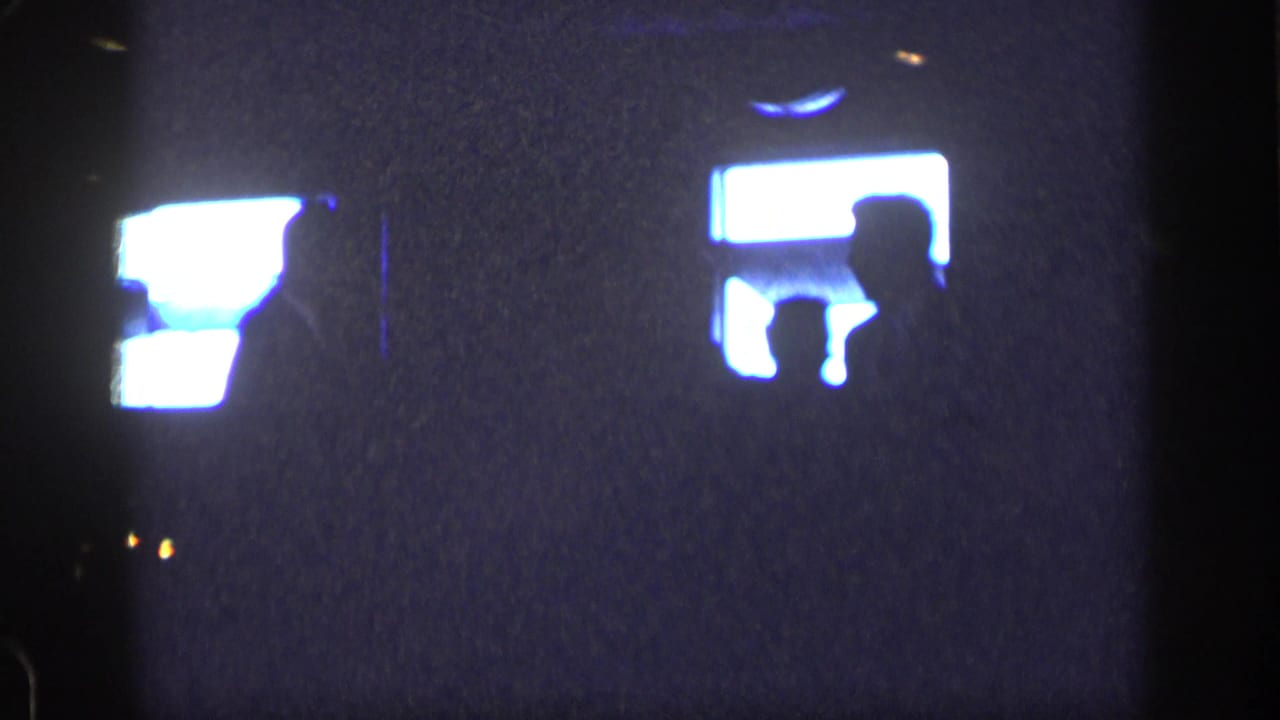 Dark 8mm home-movie frame from New York, 1957, with a silhouetted dancer crossing glowing light patches.