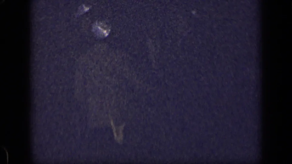 End frame from the 1957 New York 8mm clip, mostly dark with film grain and faint light traces.