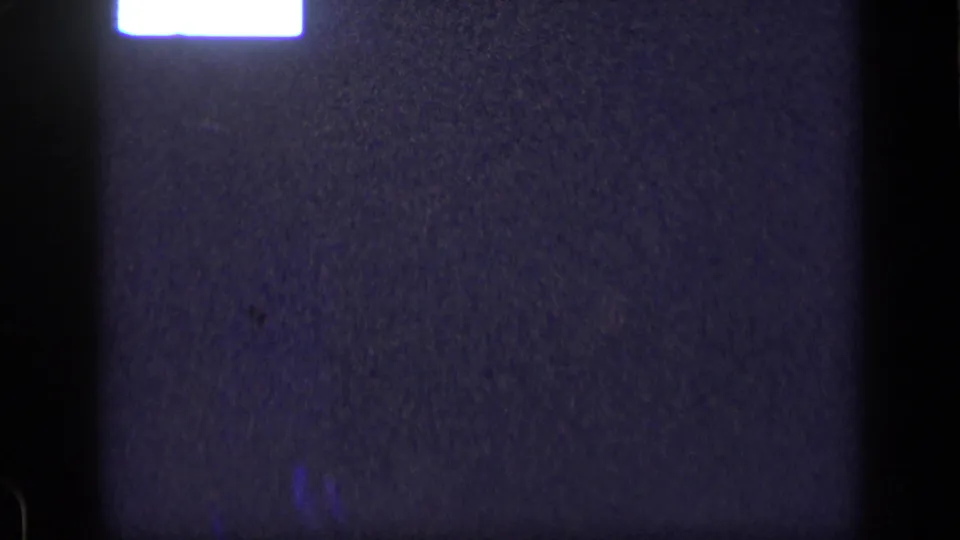 1957 New York 8mm frame with a dim blue-toned screen-like surface, a top white glow, black borders, and visible film grain.