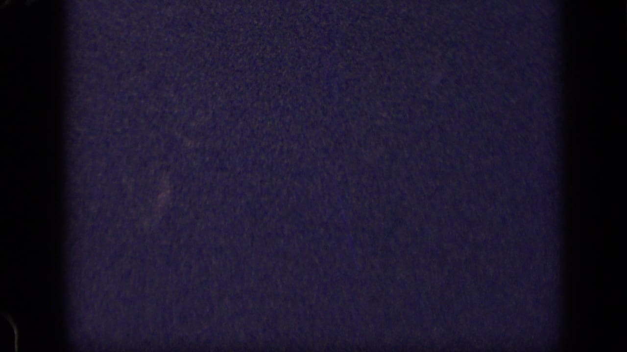 Dark, grainy film frame with vertical gate edges and little visible subject detail.