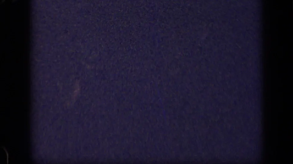 Underexposed 8mm frame from the supplied 1957 New York clip, showing mostly dark film texture, grain, and frame edges before the party scene appears.