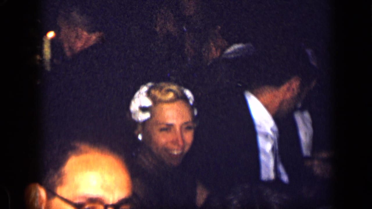 Smiling woman with light hair accessory among formally dressed dinner guests.