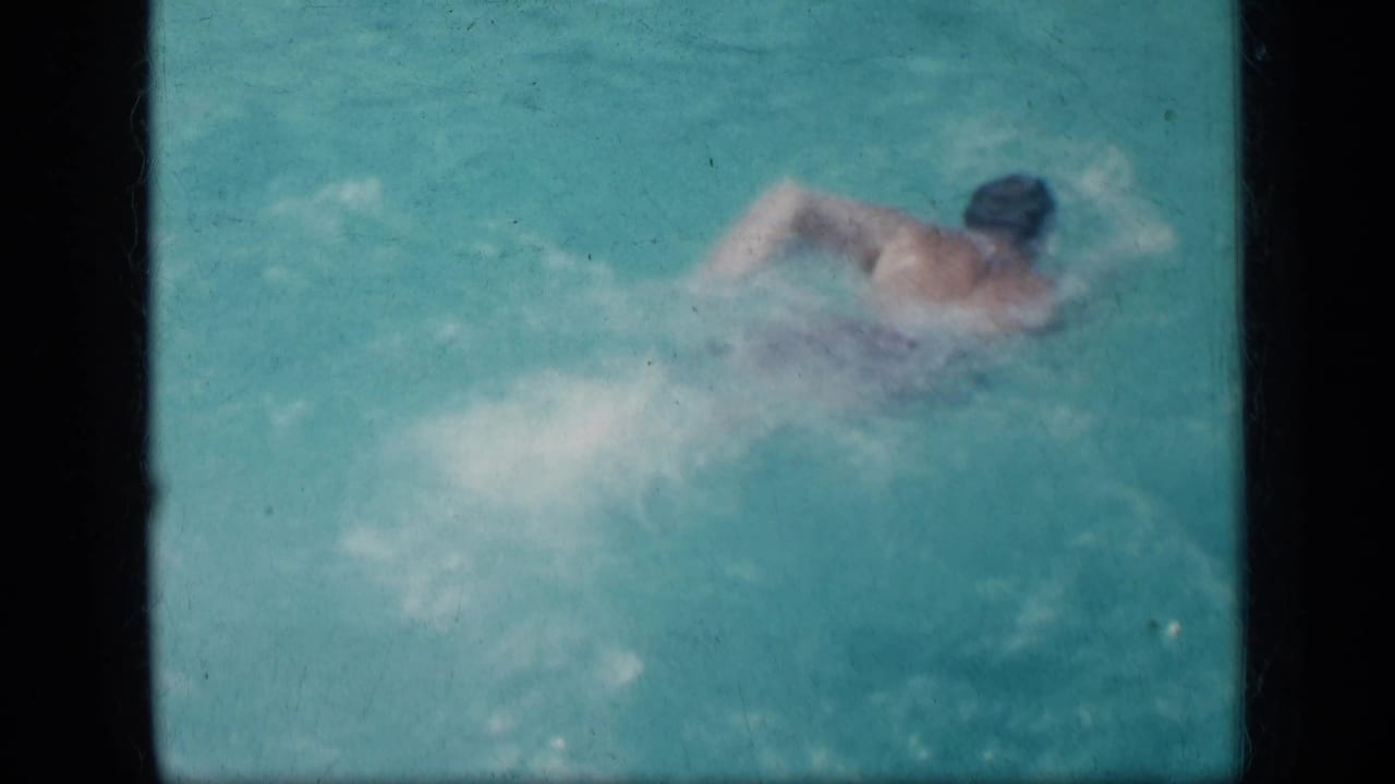 Swimmer doing a stroke across turquoise pool water.