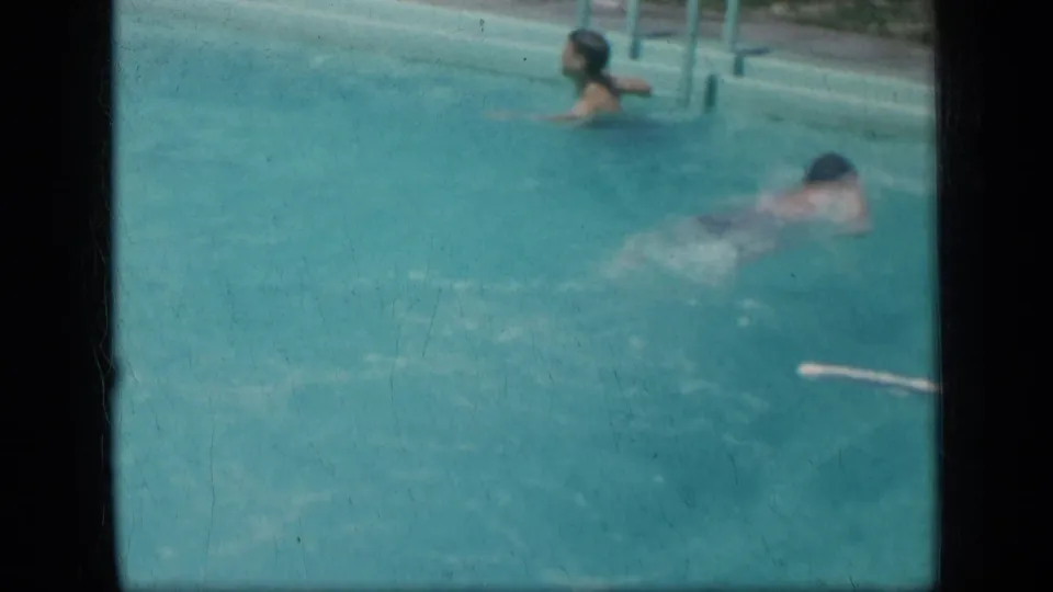 Two people are visible in the turquoise pool, one swimming and another near the pool edge or ladder in the 1957 New York footage.