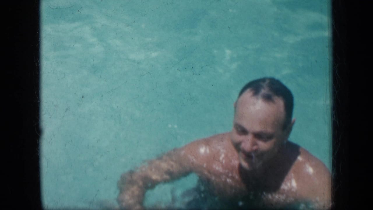 The man continues through the pool in the supported 1957 New York home-movie setting, with soft focus and bright water around him.