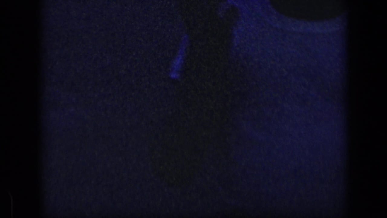 Dark frame with a partial shoulder and light shirt shape near the upper right.