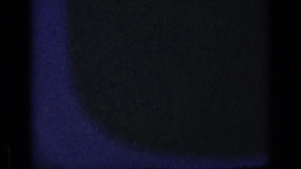 1957 New York 8mm frame showing a shadowed torso-like form in a dark interior with soft blue-black film texture.