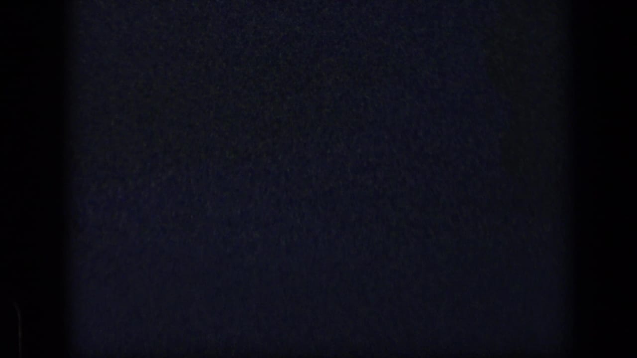 Dark grainy 8mm frame with faint blue exposure marks.