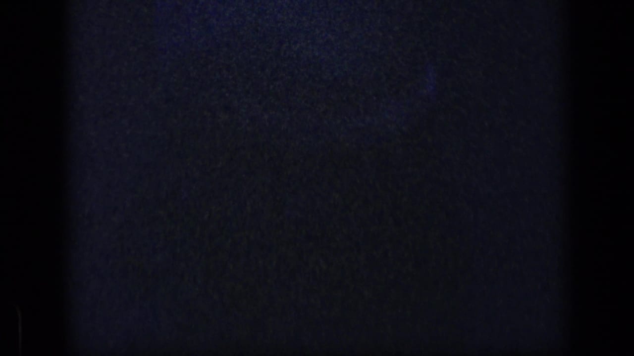 Mostly dark 8mm frame with a faint blue arc and heavy grain.