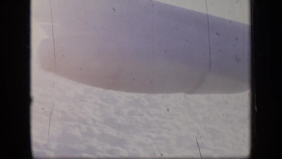 The airplane wing fills more of the frame above clouds in this 1957 8mm passenger-window view.