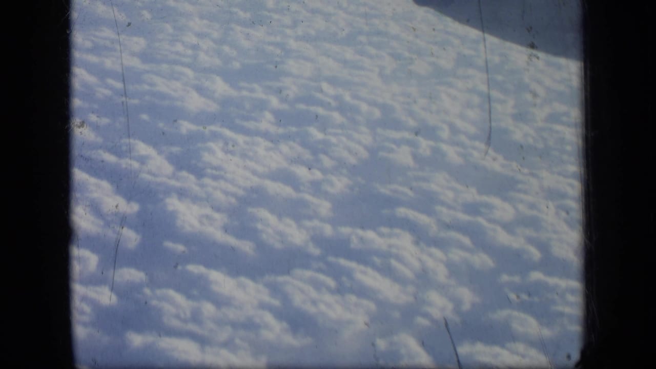 Cloud field below with a dark window divider and aircraft structure above.