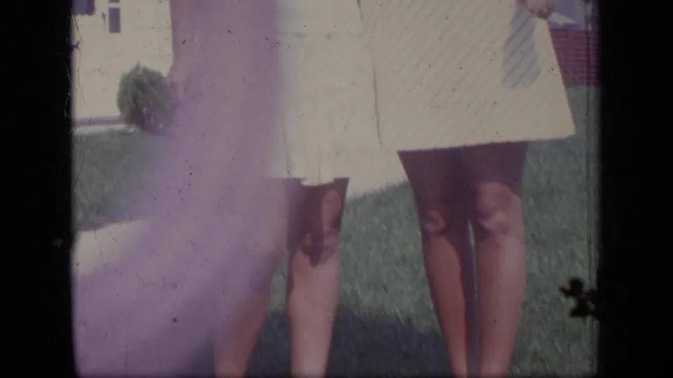 The final frame shows the women standing arm in arm on a green lawn, with the house and bright yard light behind them.