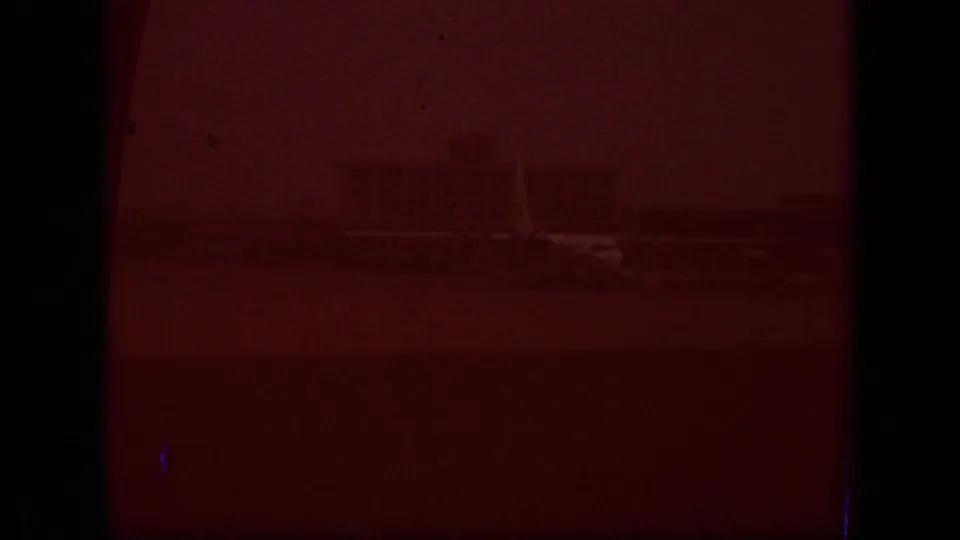 The final frame appears mostly red and underexposed, with faint outlines of the exterior setting barely visible on the film scan.