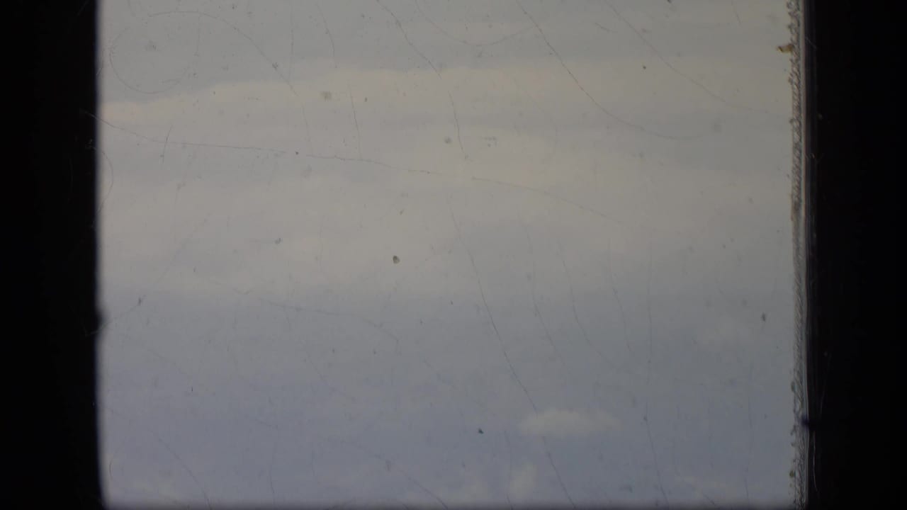 Airplane-window view of pale clouds and haze in a 1970 New Jersey 8mm home-movie frame.