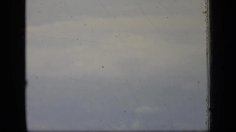 Airplane-window view of pale clouds and haze in a 1970 New Jersey 8mm home-movie frame.